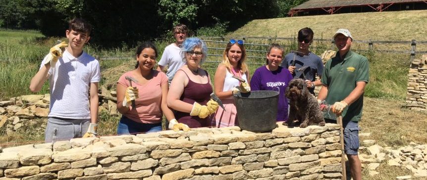 A group of people by a dry stone wall in the Cotswolds