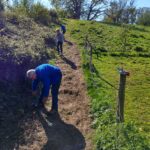 Two wardens preparing the mud track on slope where the steps will be going in to make access easier.