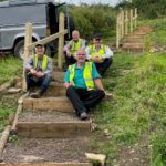 4 wardens in yellow high vis jackets sitting on the part completed steps taking a well earned break