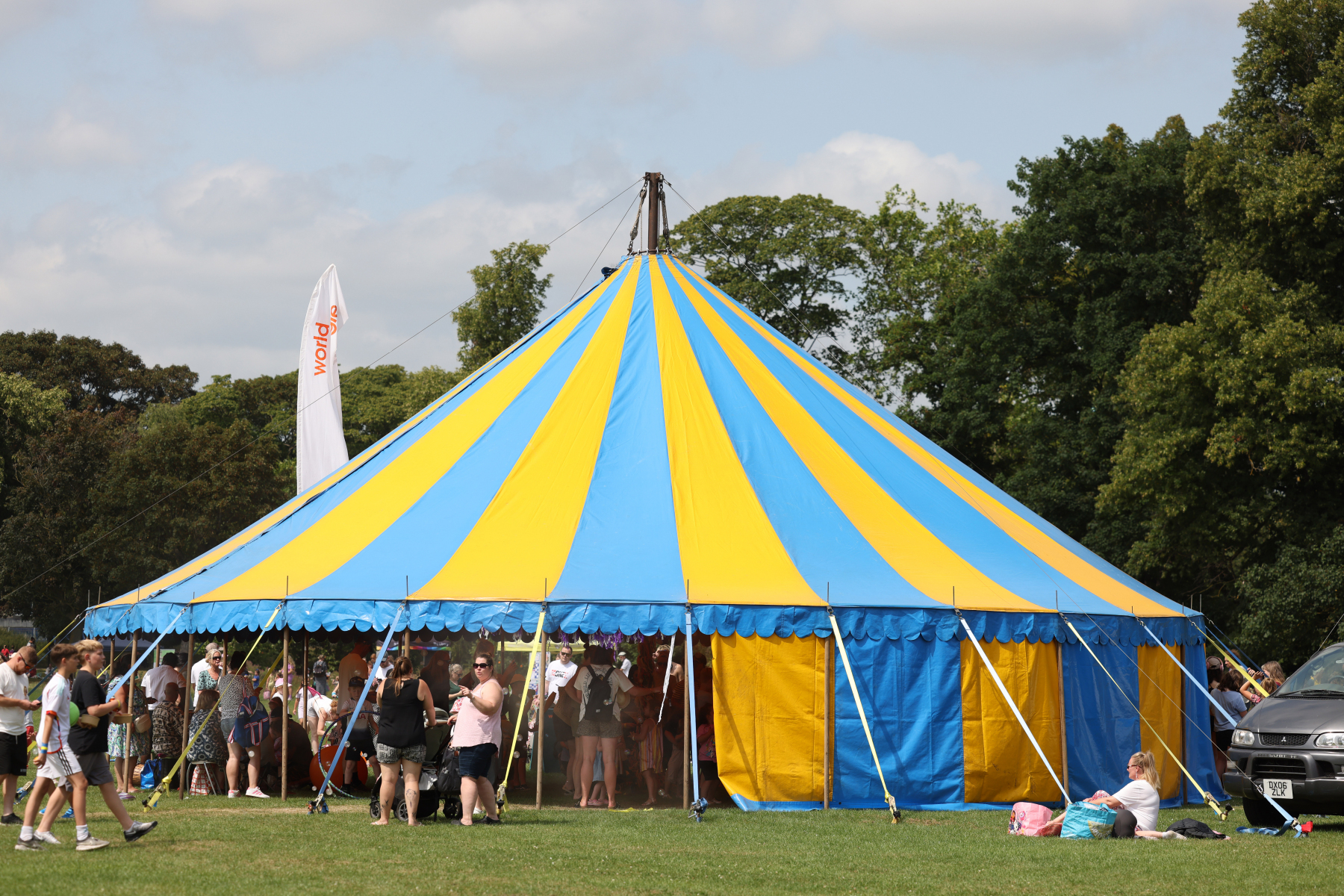 Image is a photo of a blue and yellow big top tent with people going in and out.
